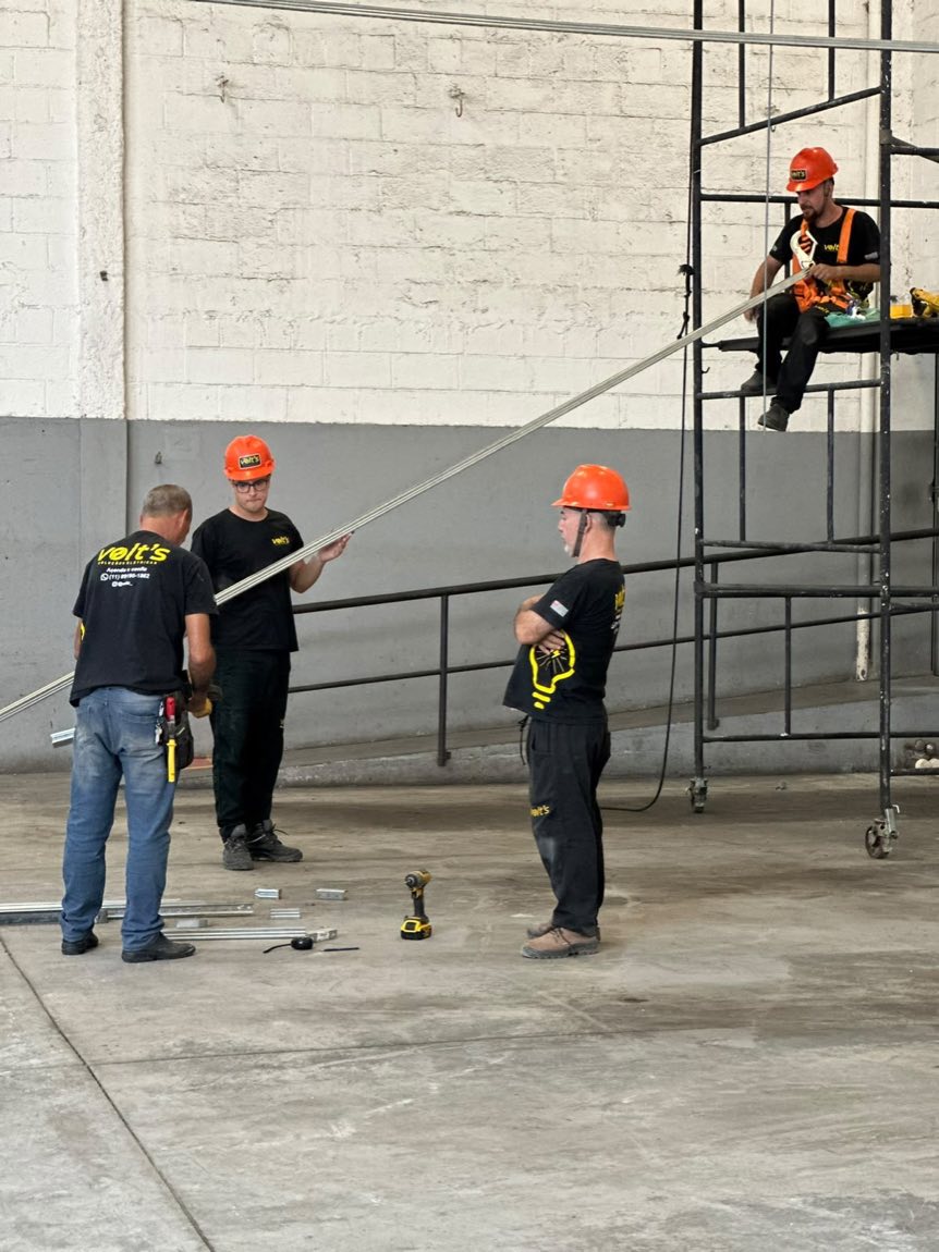 Equipe da Volt's com capacetes trabalhando em andaime dentro de um galpão