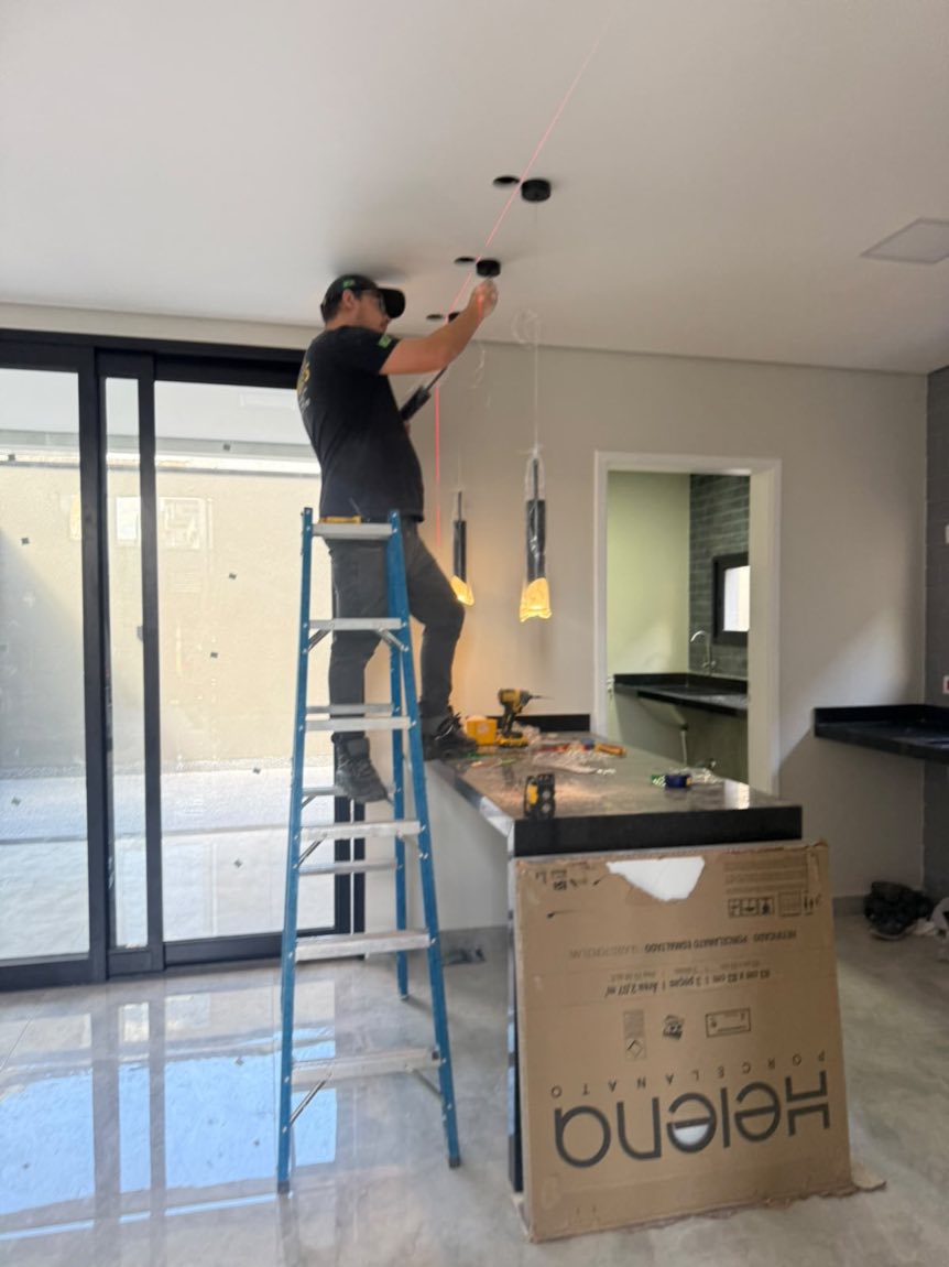 Profissional da Volt's instalando pendentes pretos sobre bancada de cozinha