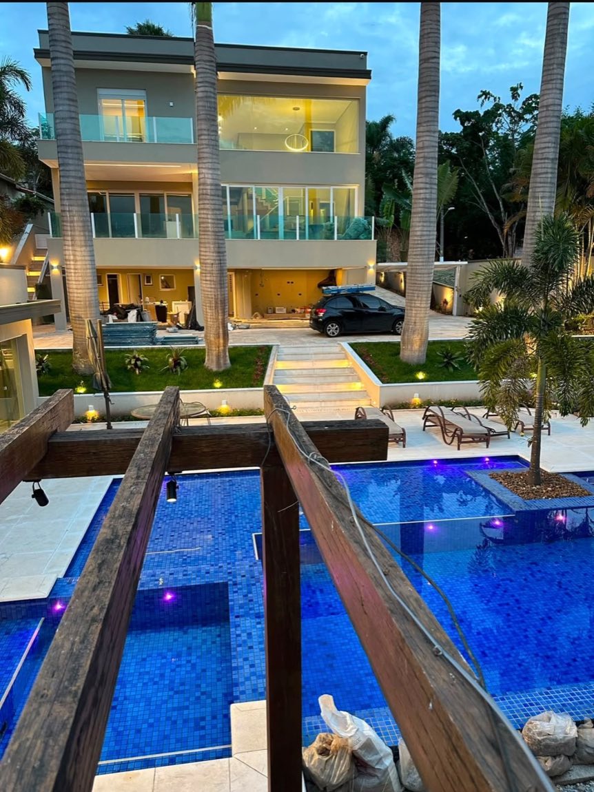 Fachada iluminada de residência de alto padrão com piscina em primeiro plano