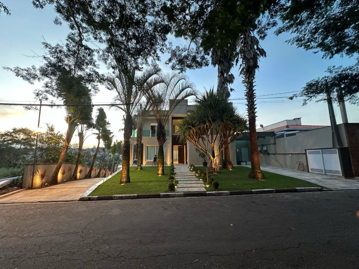 Fachada de residência de alto padrão à noite com jardim e caminho iluminados