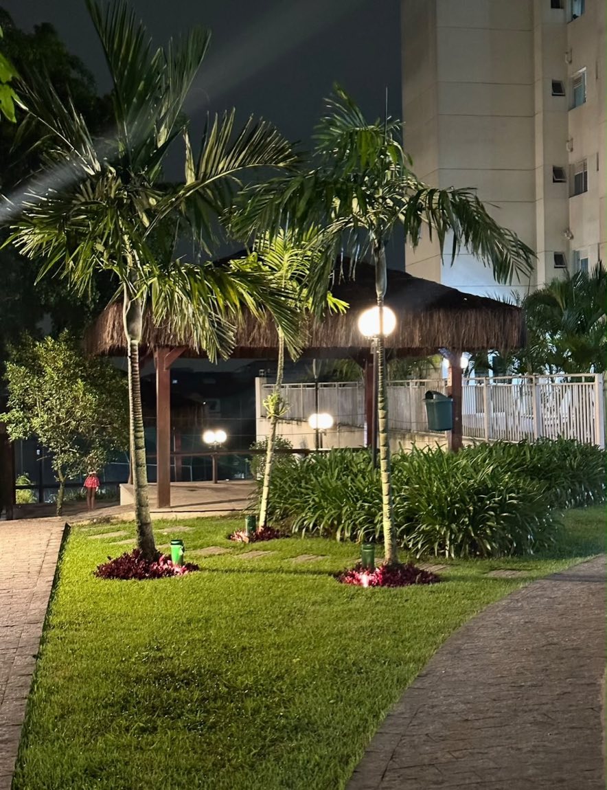 Jardim iluminado à noite com poste e luminárias externas