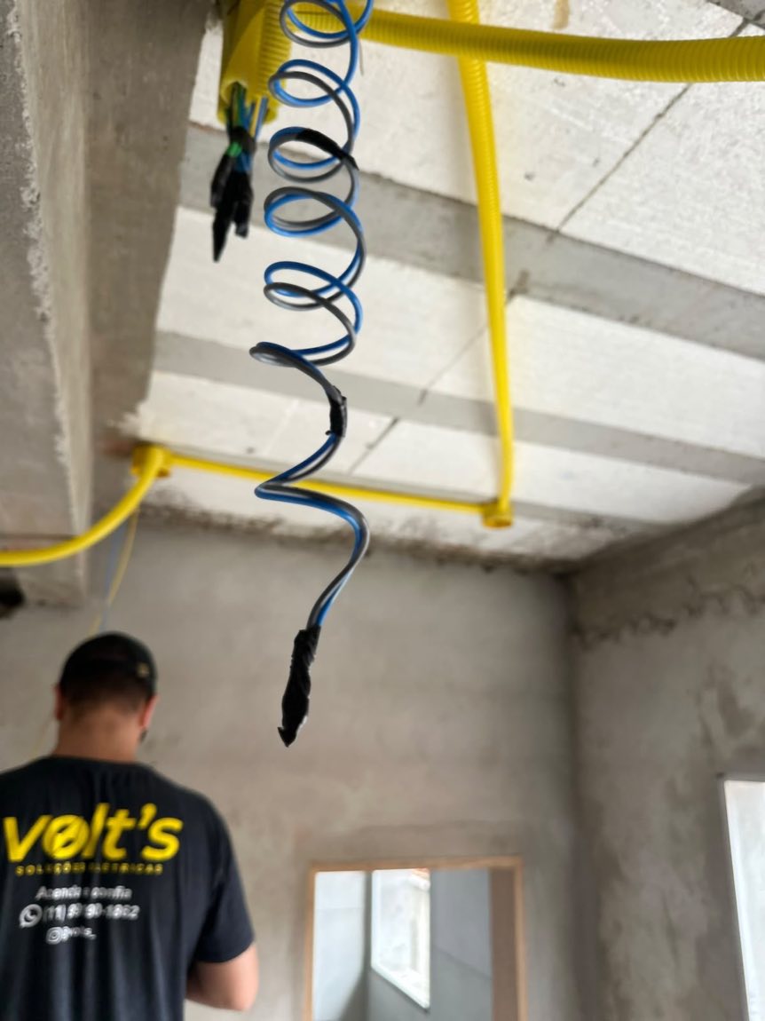 Profissional da Volt's puxando cabo elétrico no teto de uma obra de pé-direito alto