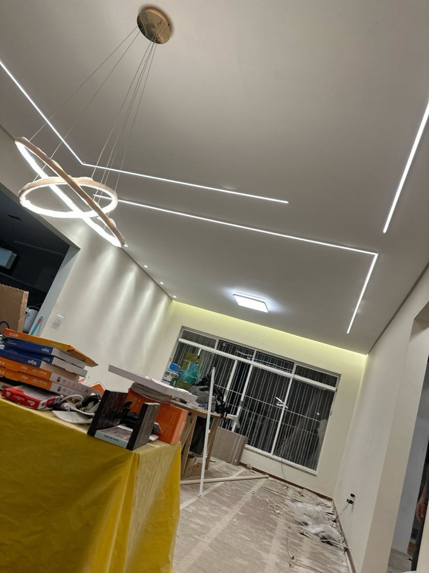 Sala residencial com perfis de LED desenhados no forro e pendente circular
