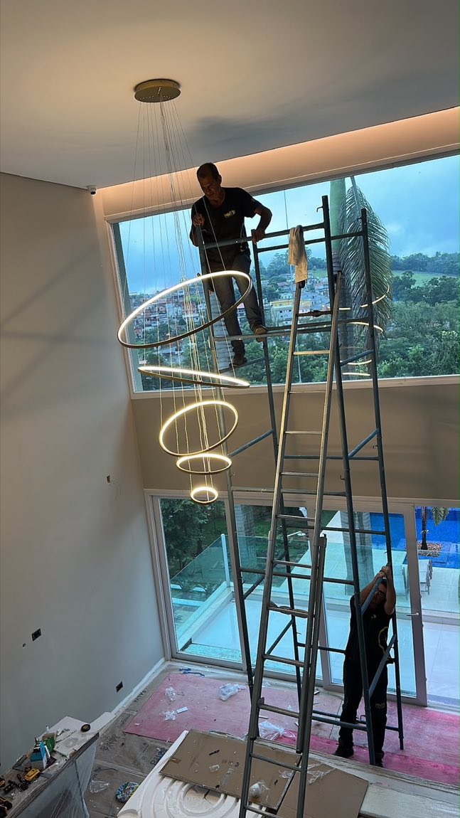 Equipe da Volt's instalando pendente de anéis de LED em sala de pé-direito duplo