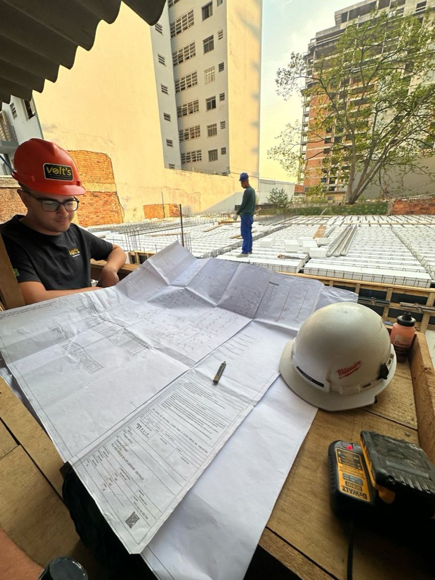 Profissional da Volt's com capacete analisando a prancha do projeto elétrico na obra