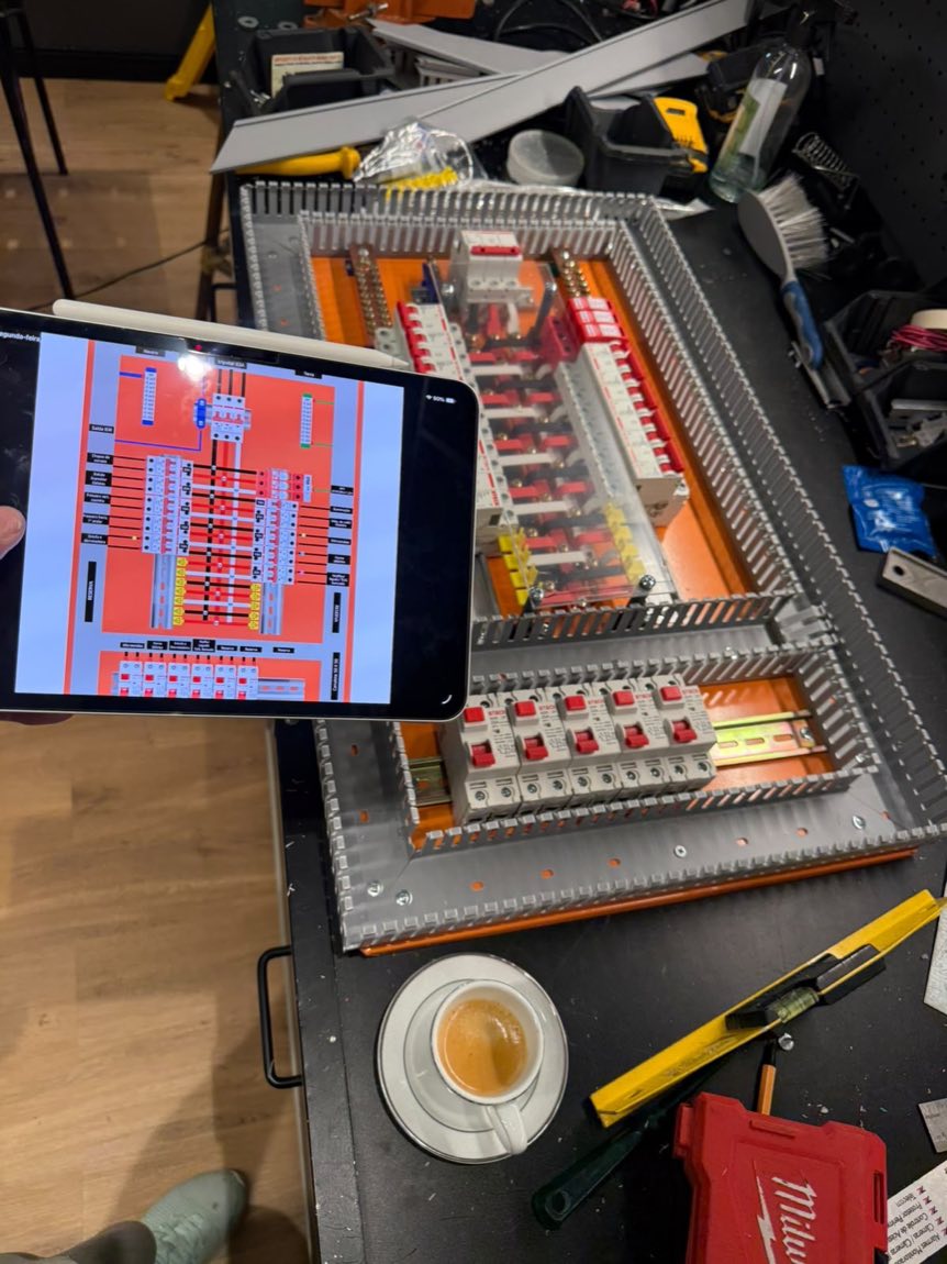 Tablet com diagrama elétrico ao lado de painel sendo montado na bancada