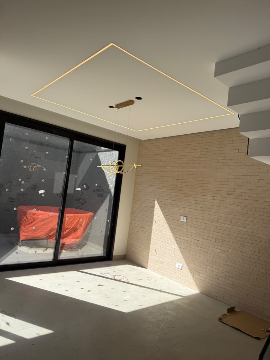 Sala residencial com perfil de LED quadrado embutido no forro e pendente dourado
