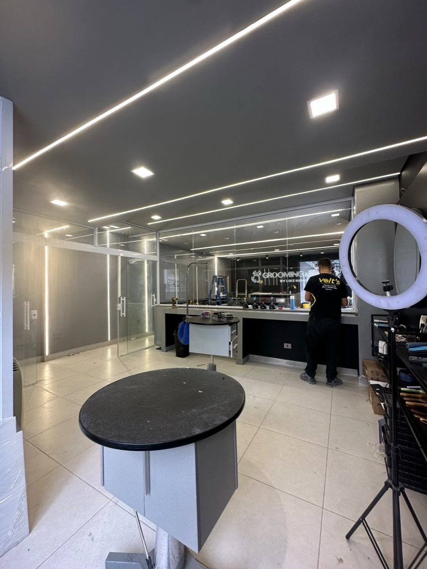 Salão comercial com perfis de LED lineares embutidos no forro e spots sobre as bancadas