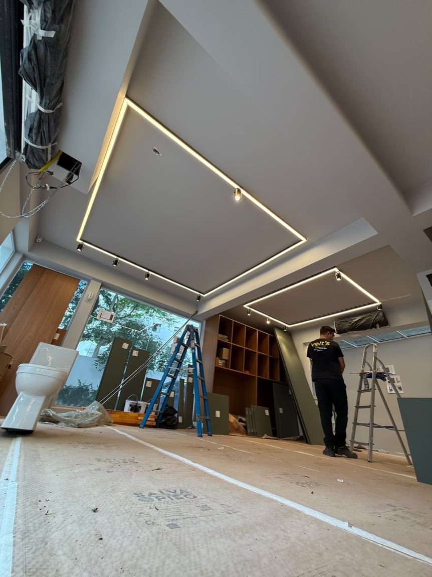Ambiente amplo em obra com sanca de LED contínua acesa no forro