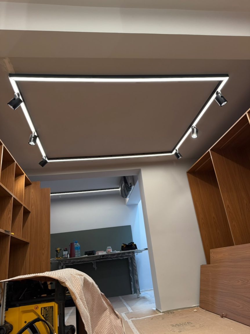 Ambiente comercial com sanca de LED retangular no teto e marcenaria em madeira