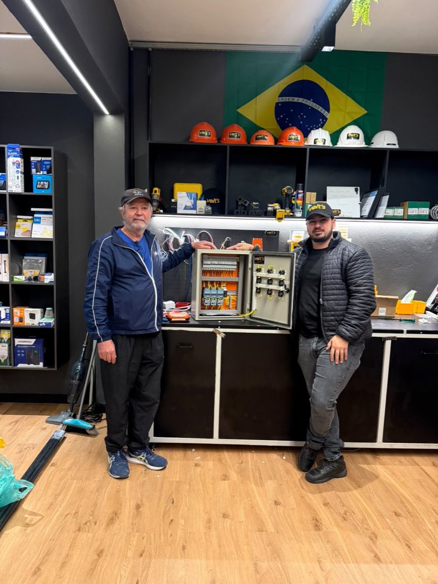Equipe da Volt's na loja, ao lado de um quadro elétrico montado na oficina